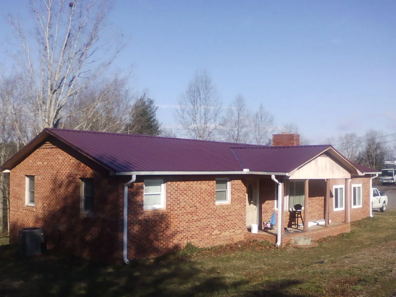 Burgundy metal roof on a brick ranch home with a new addition in Eau Claire