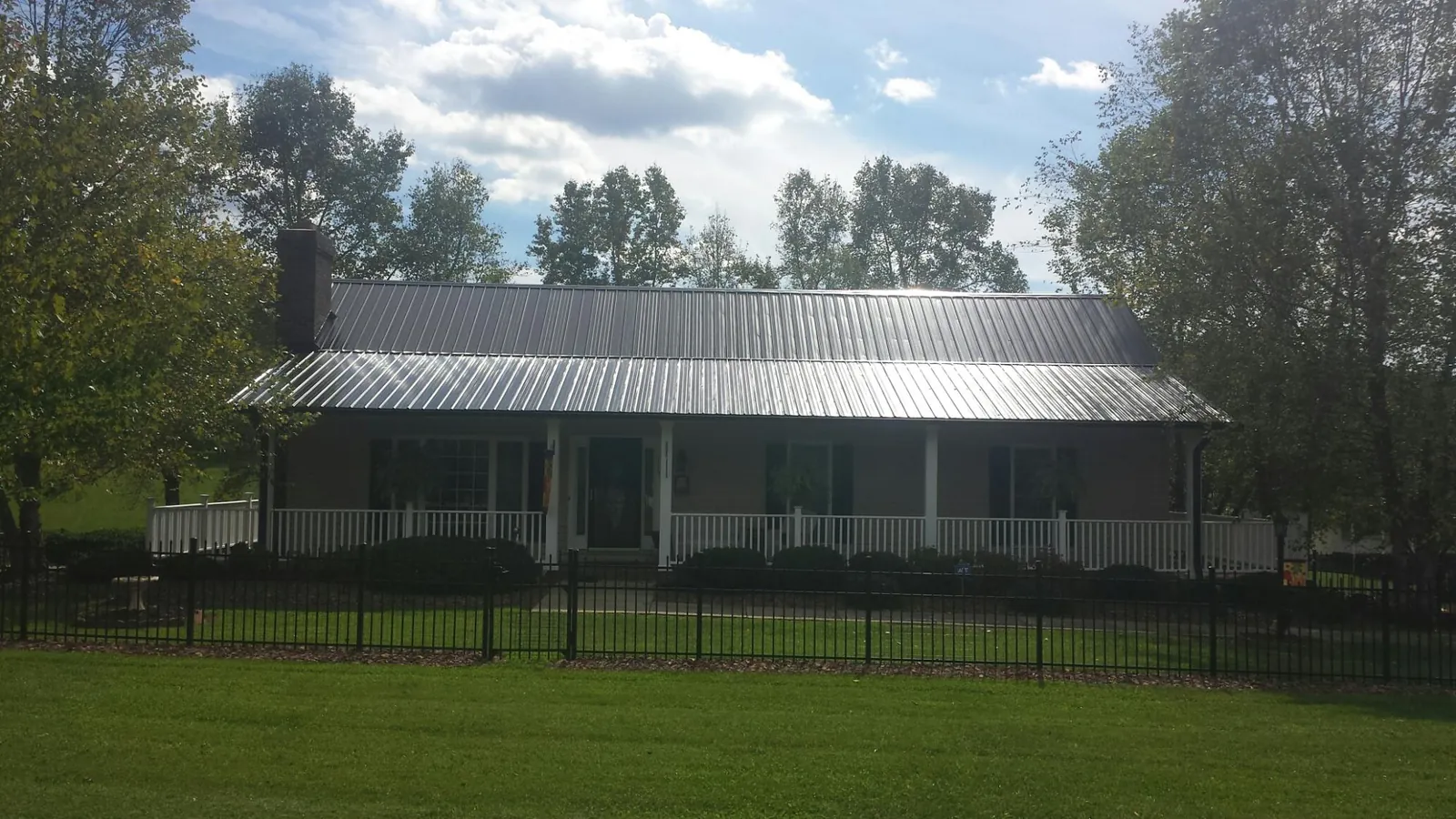 Gray metal roof on a brick ranch with a full width front porch — Gutter Guard Installation work by our crew in Eau Claire